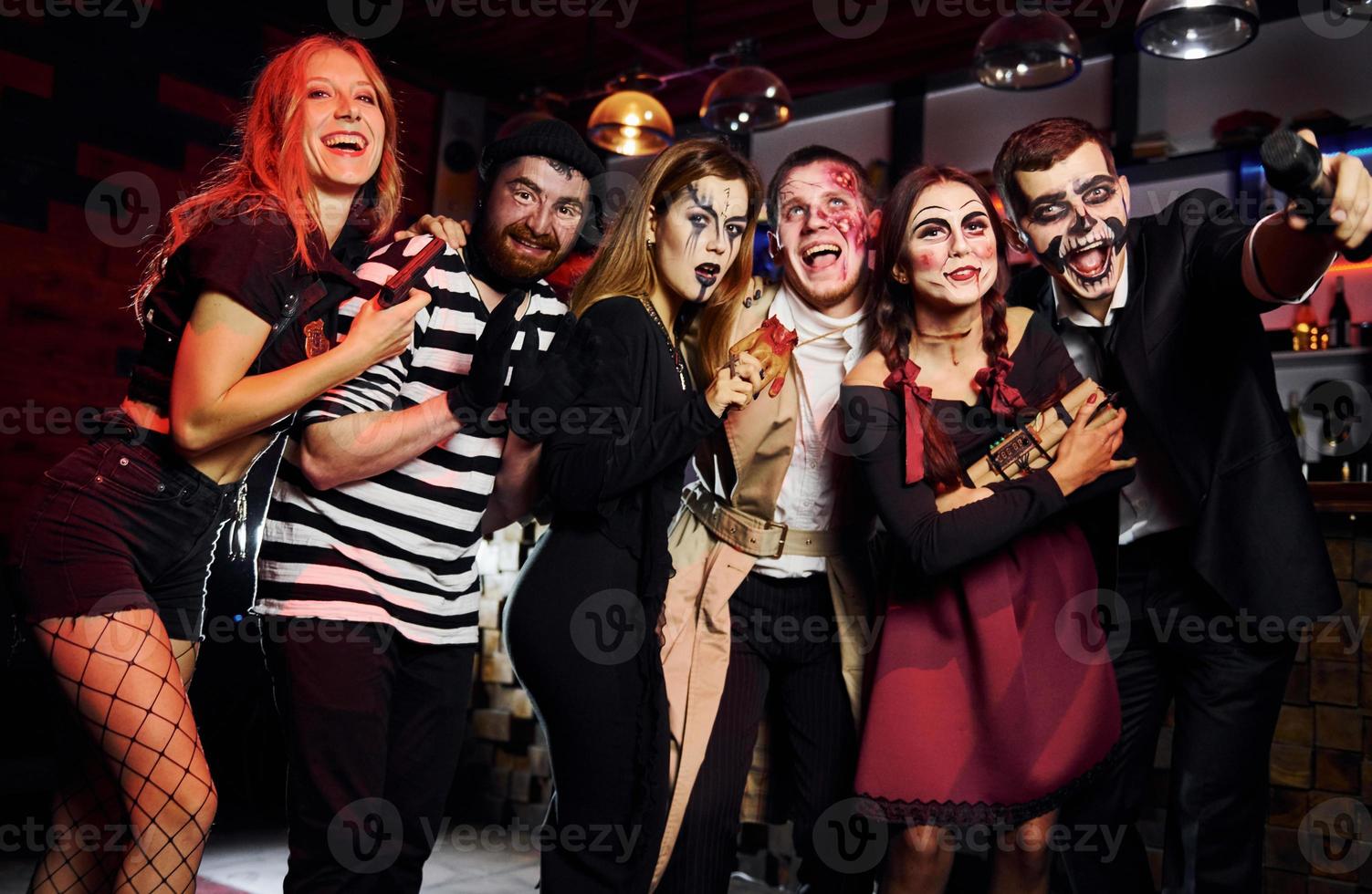 Friends is on the thematic halloween party in scary makeup and costumes have fun and posing for the camera together photo