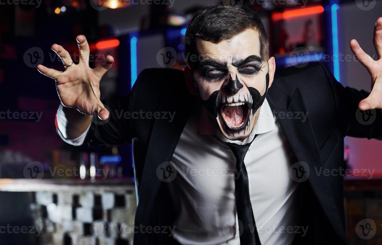 gritando a la cámara. retrato de hombre que está en la fiesta temática de halloween con maquillaje y disfraz de esqueleto aterrador foto