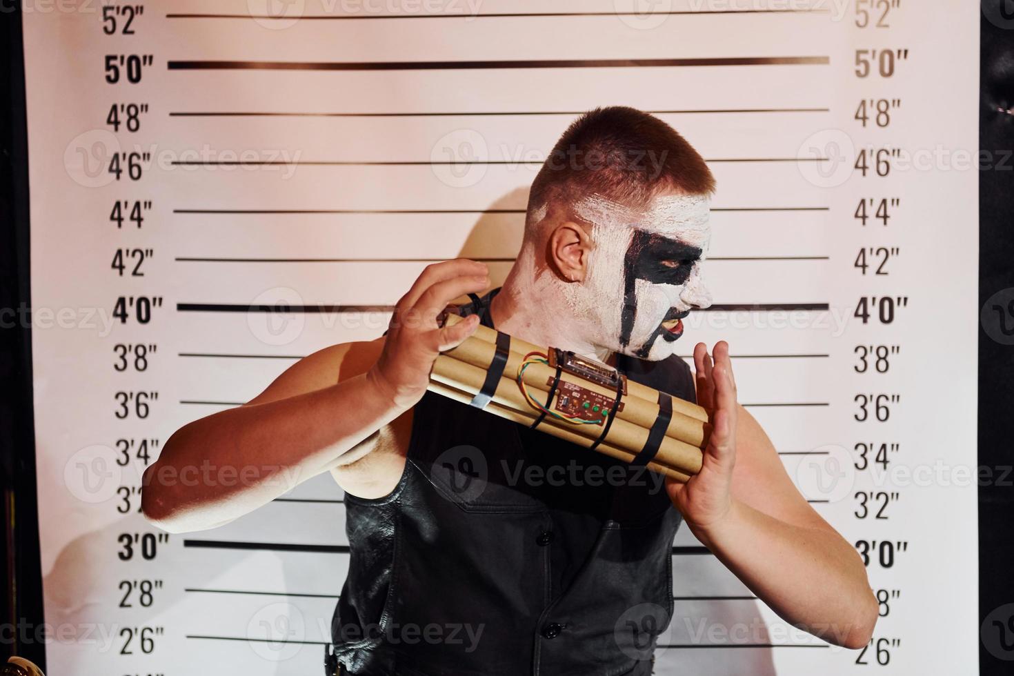 Portrait of man that is on the thematic halloween party in scary black metal makeup and costume with bomb in hands photo