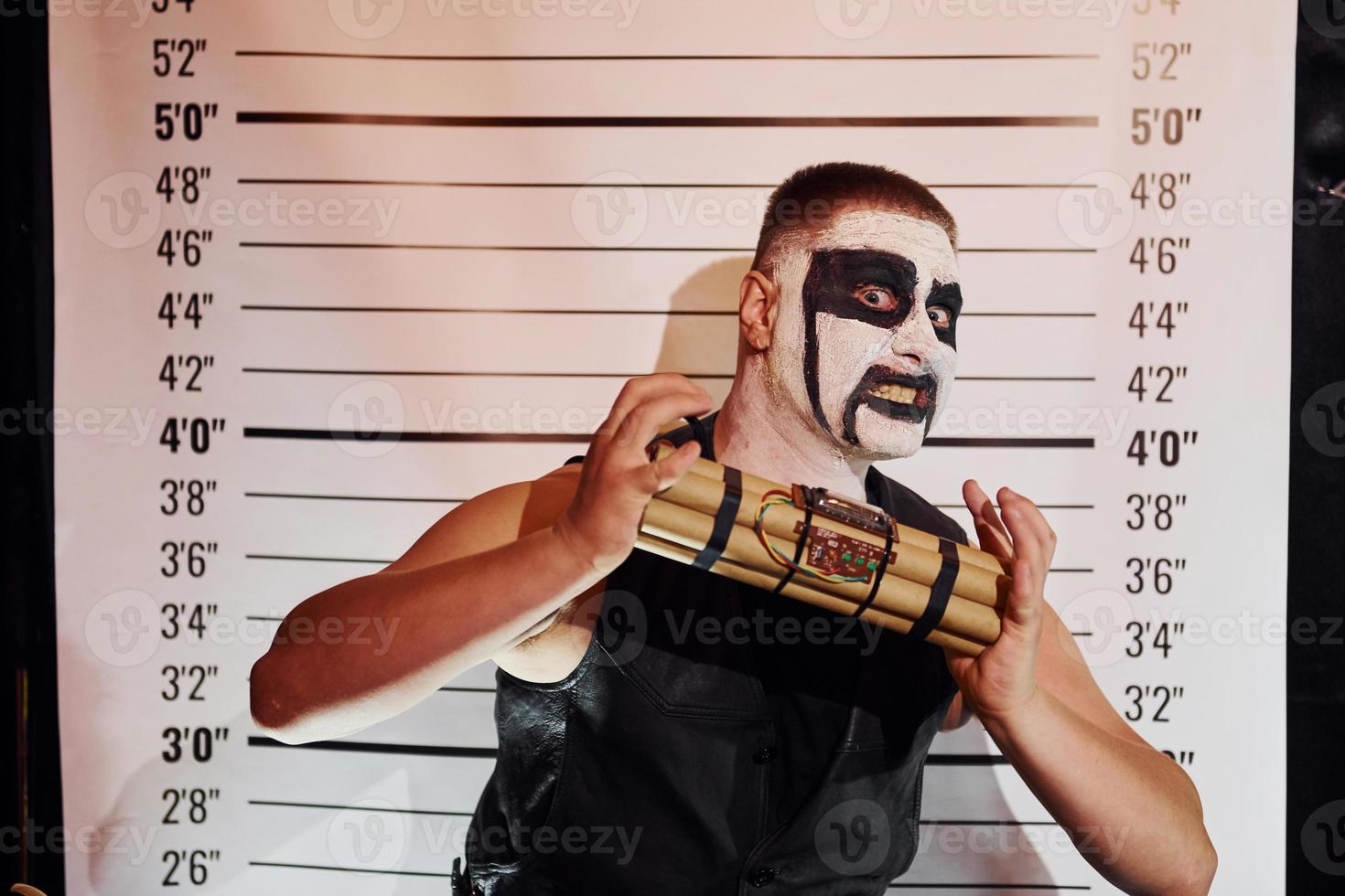 Portrait of man that is on the thematic halloween party in scary black metal makeup and costume with bomb in hands photo