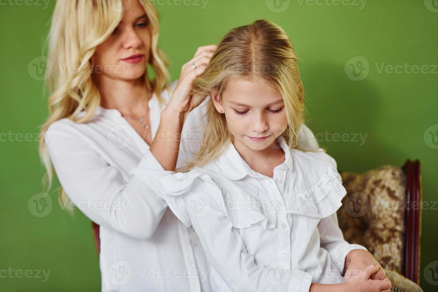 Mother with her daughter together in the studio with green background photo