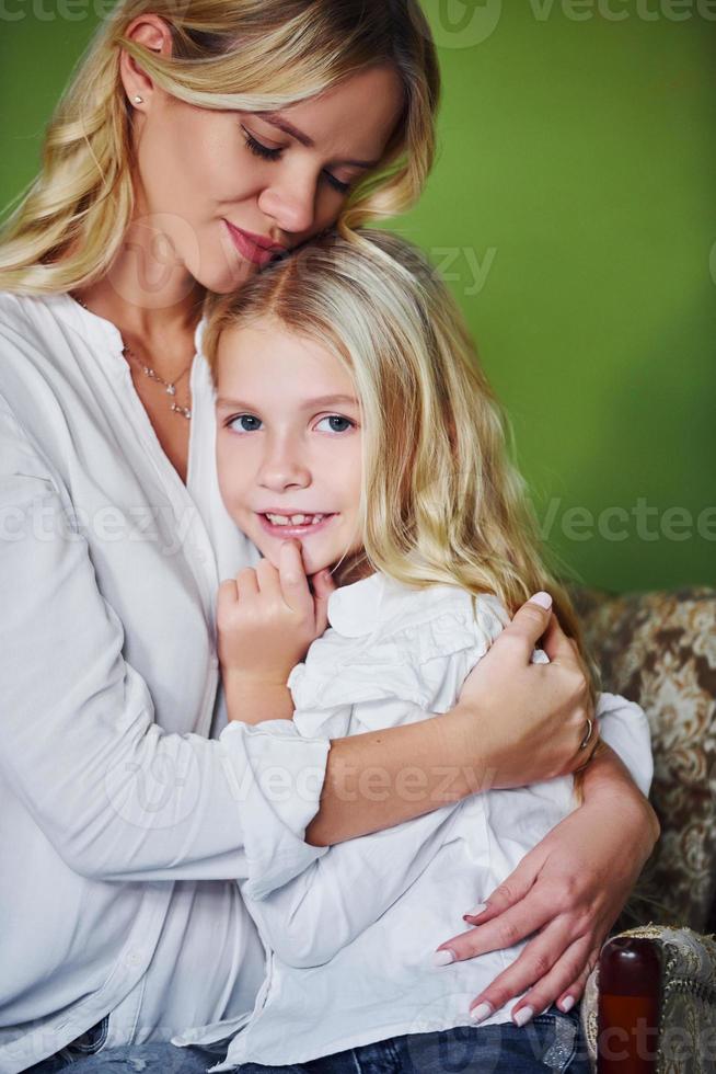 madre con su hija juntas en el estudio con antecedentes verdes abrazándose foto