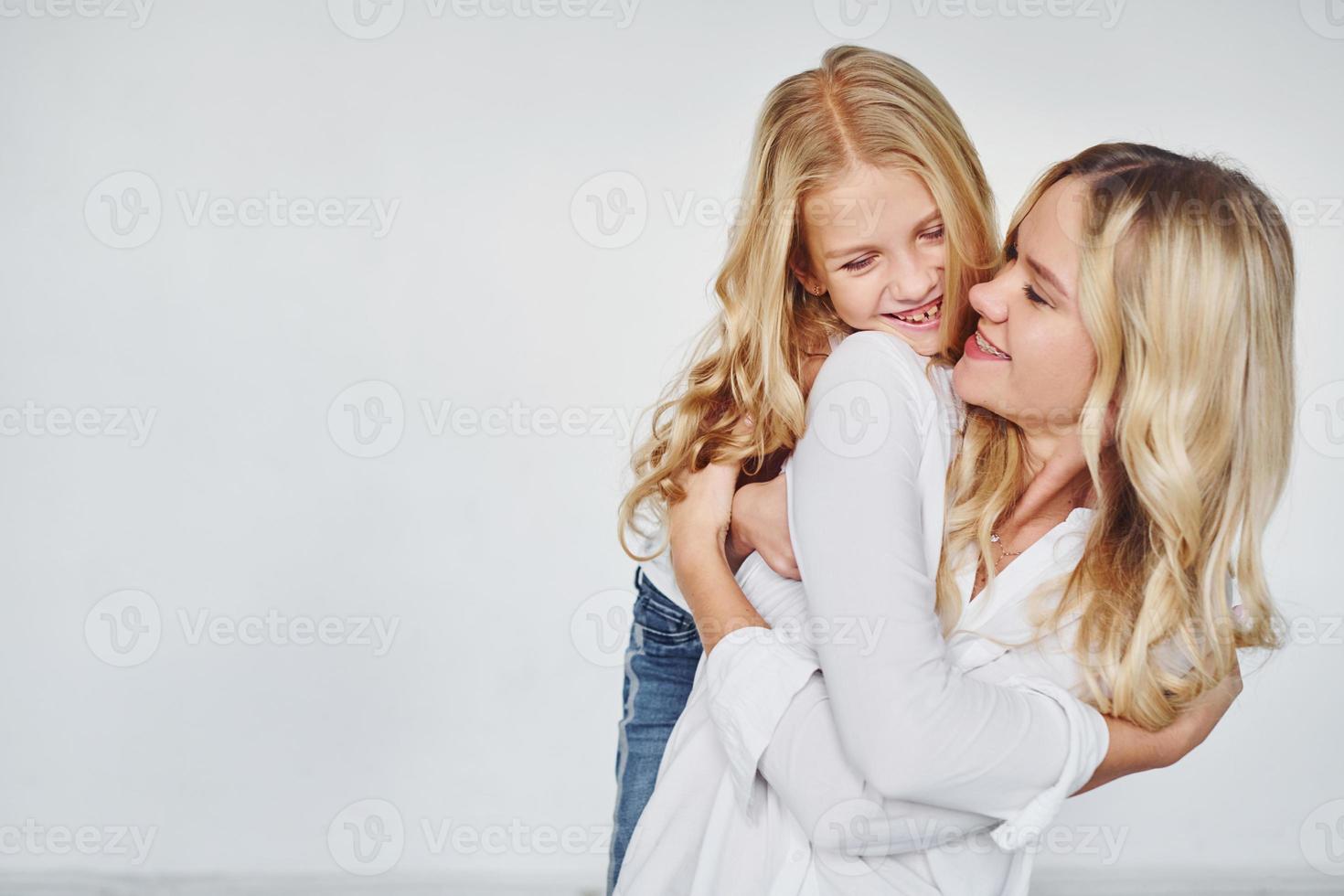 madre con su hija se divierten juntas en el estudio con fondo blanco foto