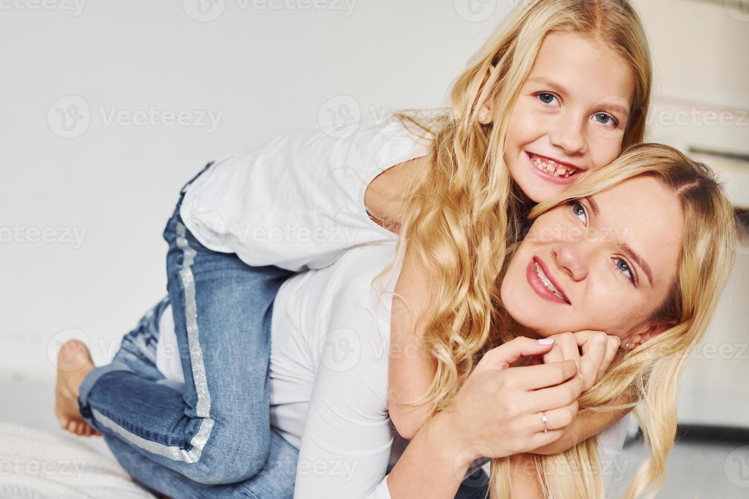 Mother with her daughter together is on the ground in the studio with white background photo