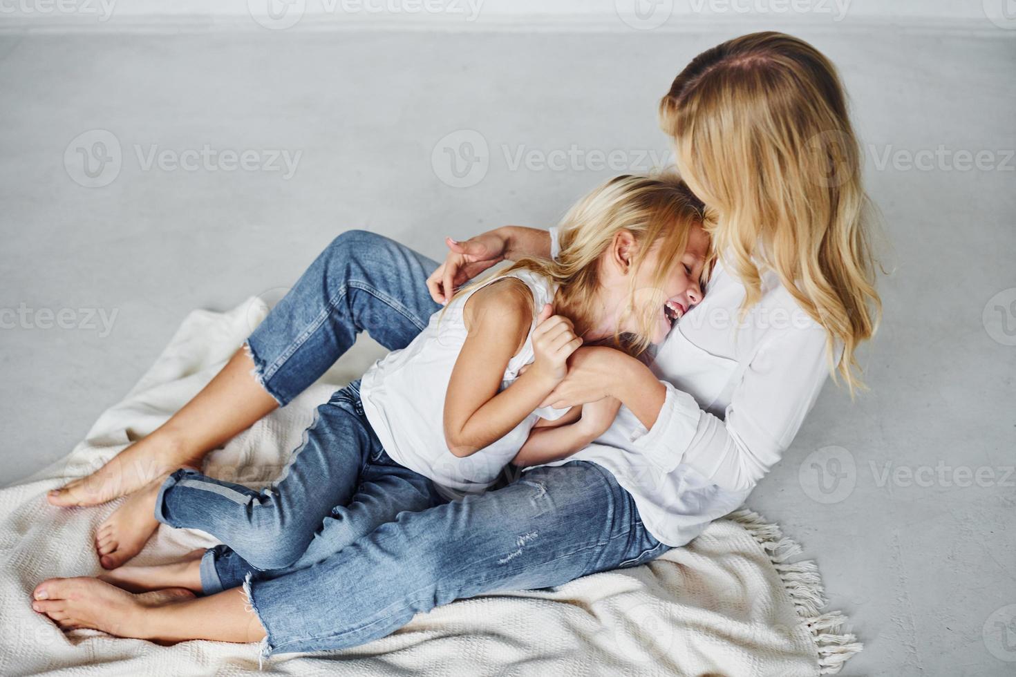 madre con su hija juntas está en el suelo en el estudio con antecedentes blancos foto