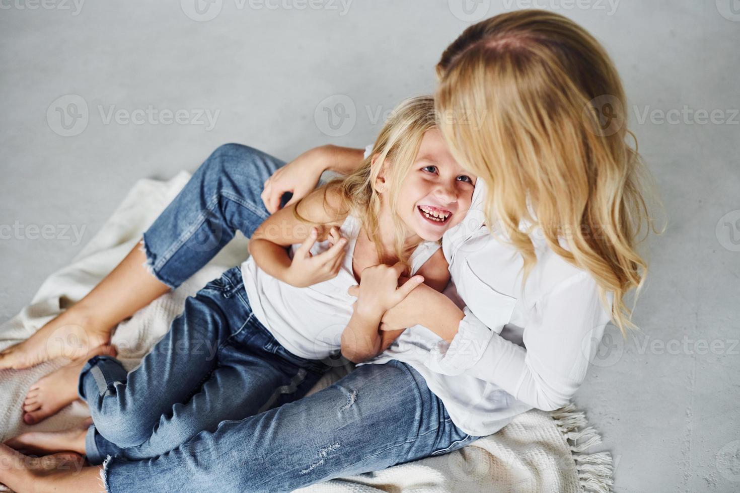 madre con su hija juntas está en el suelo en el estudio con antecedentes blancos foto