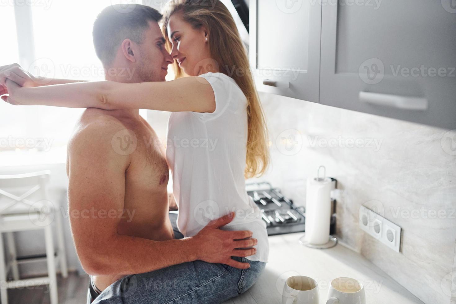 Young couple embracing and kissing each other on the kitchen photo