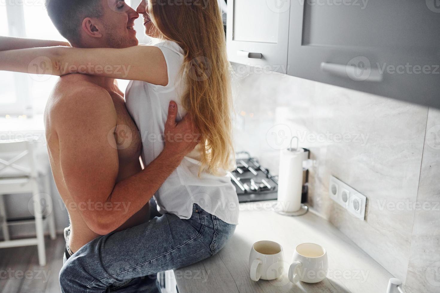 Young couple embracing and kissing each other on the kitchen photo