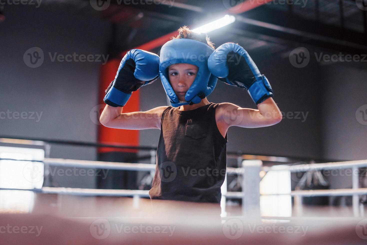 Boy in sportive protective equipment standing on the boxing ring and celebrating victory photo