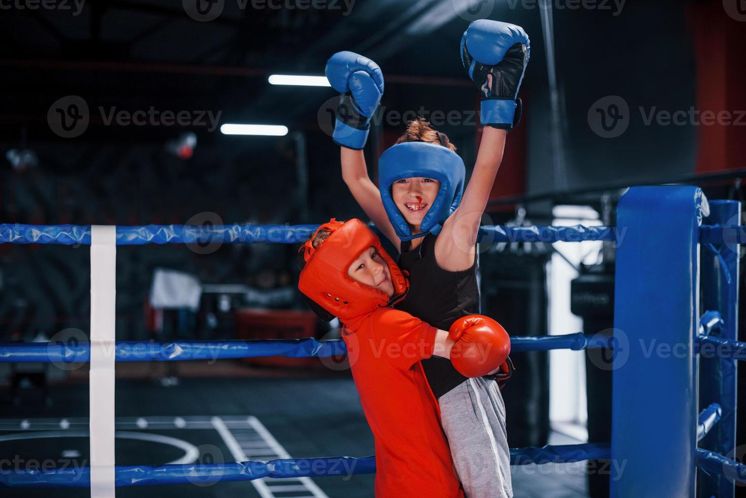 retrato de dos jóvenes con guantes protectores celebrando la victoria en el ring de boxeo foto