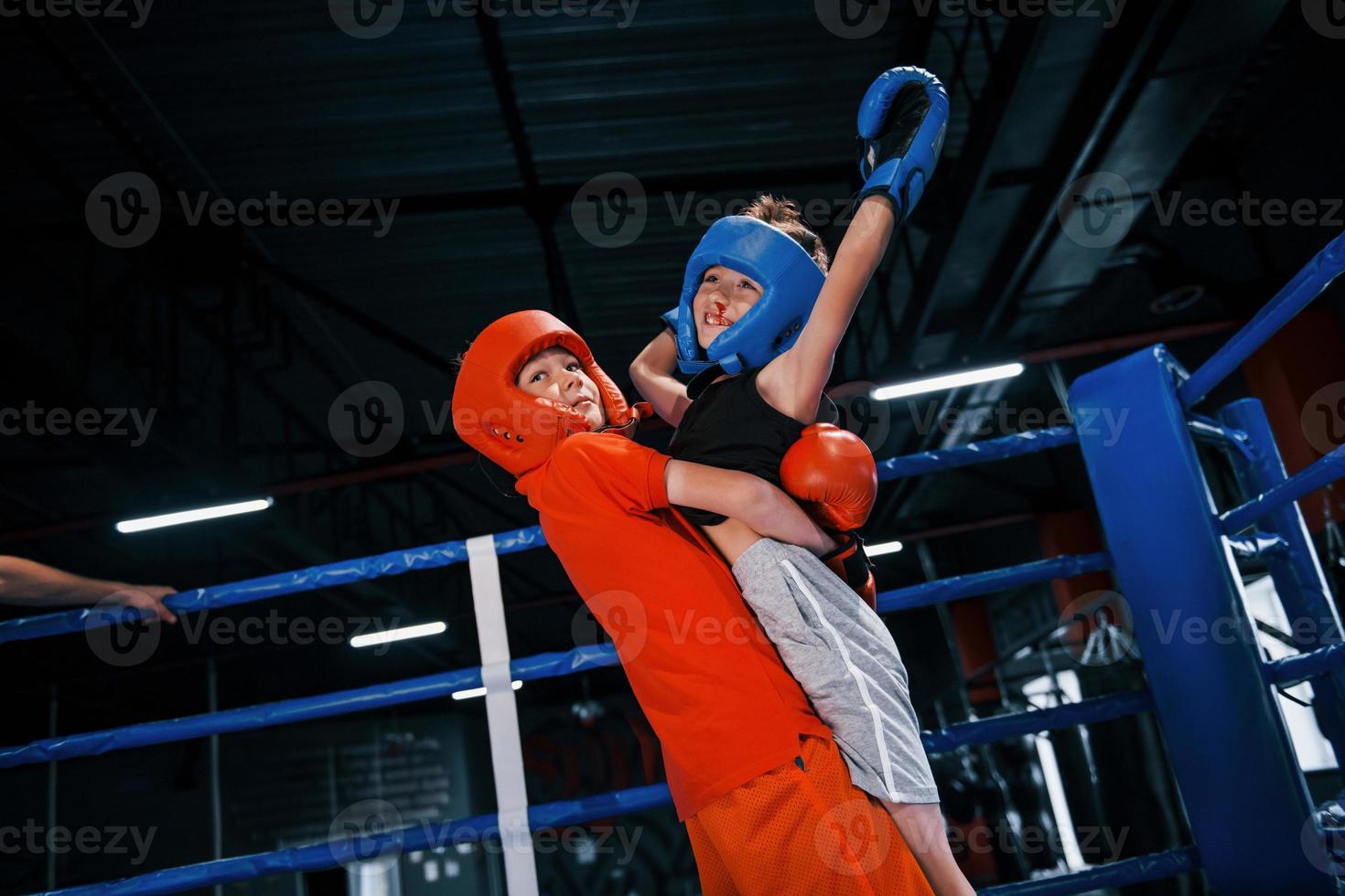 retrato de dos jóvenes con guantes protectores celebrando la victoria en el ring de boxeo foto