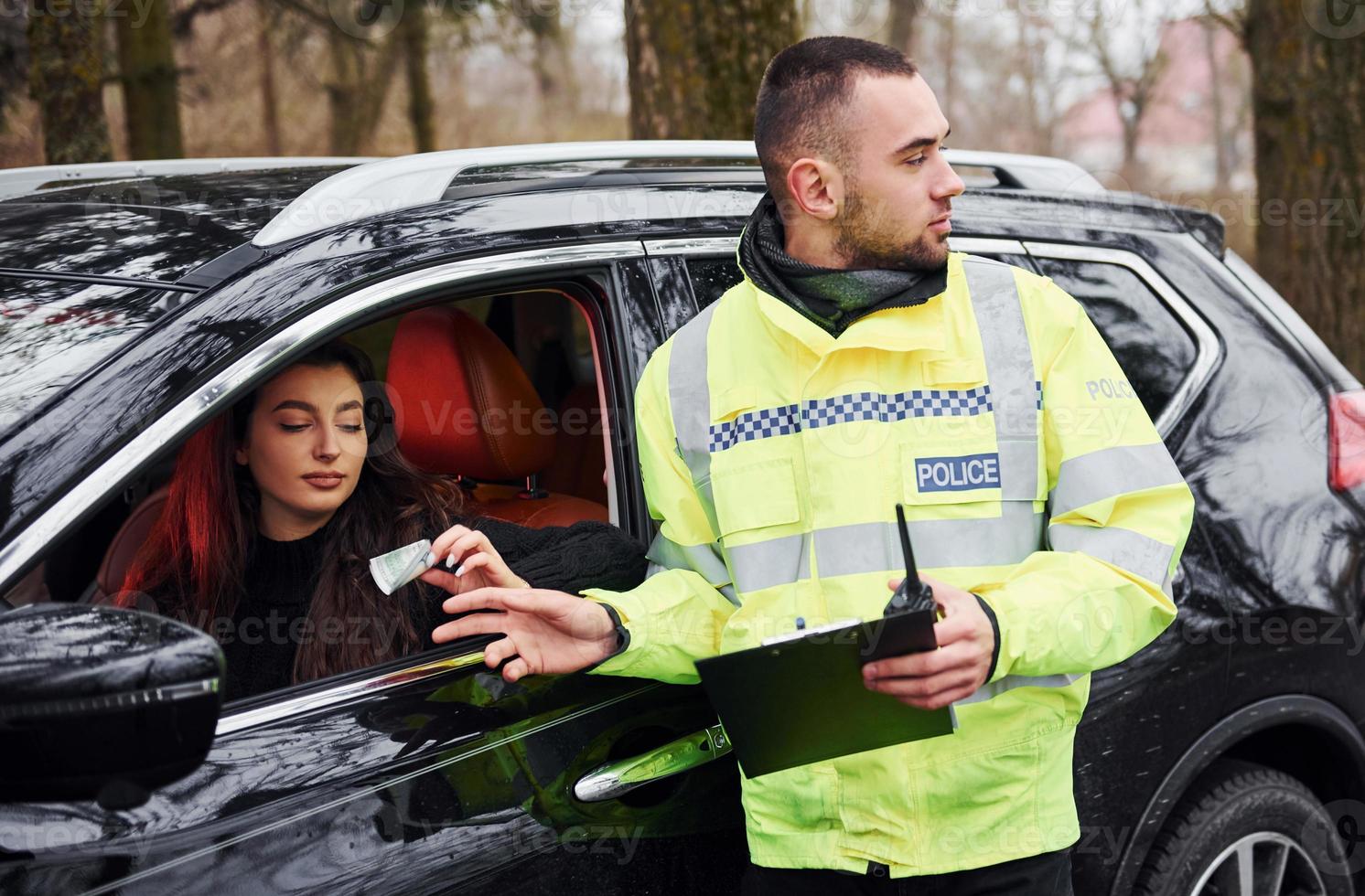 oficial de policía masculino en uniforme verde acepta soborno de mujer en coche foto