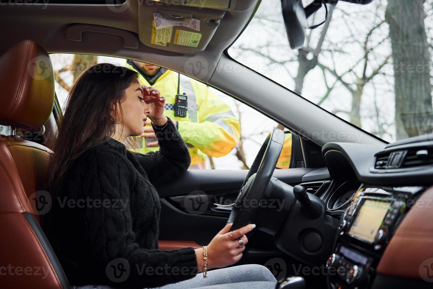 chicas se siente mal. oficial de policía masculino con uniforme verde revisando el vehículo en la carretera foto