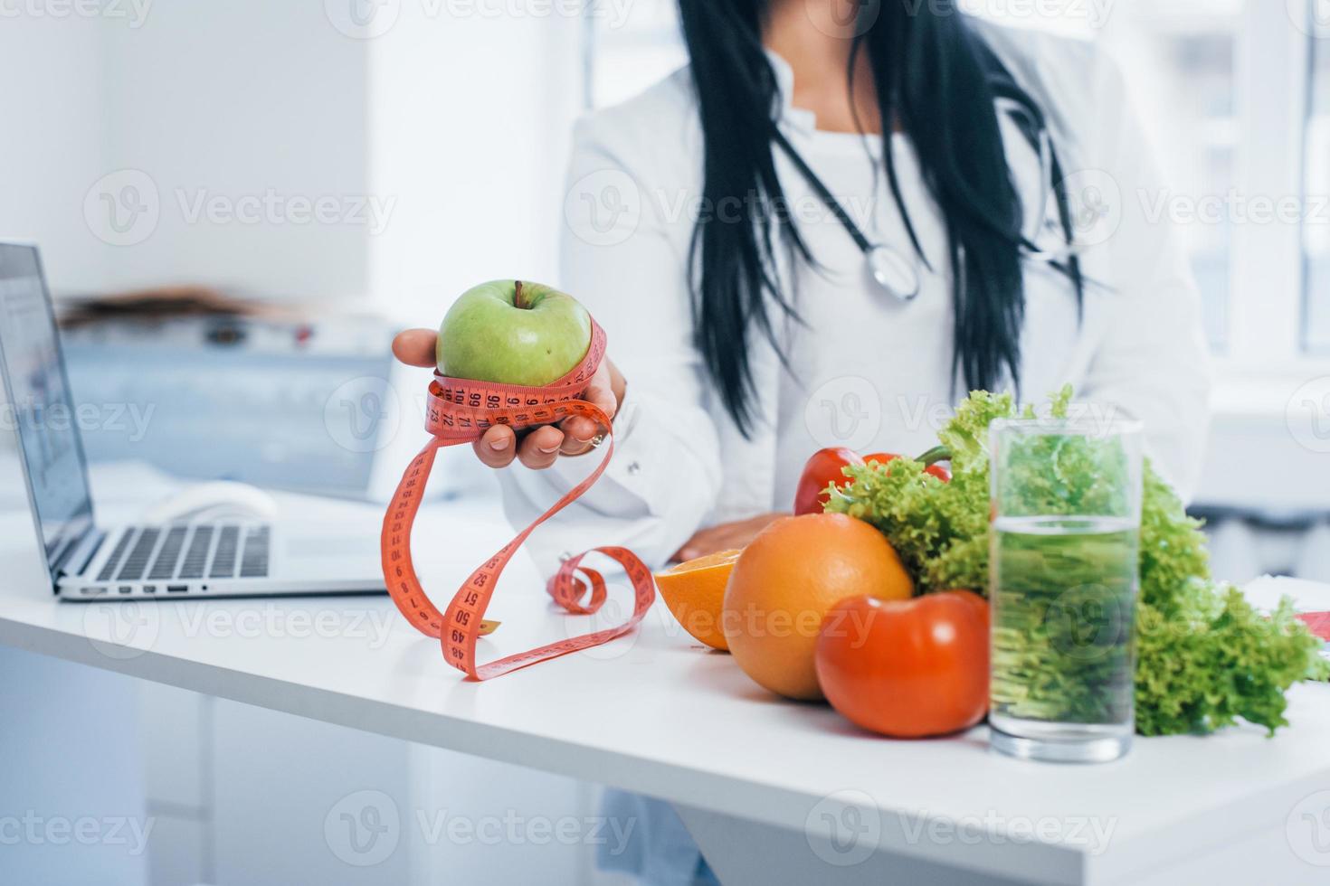 nutricionista femenina con bata blanca sentada en el interior de la oficina en el lugar de trabajo foto