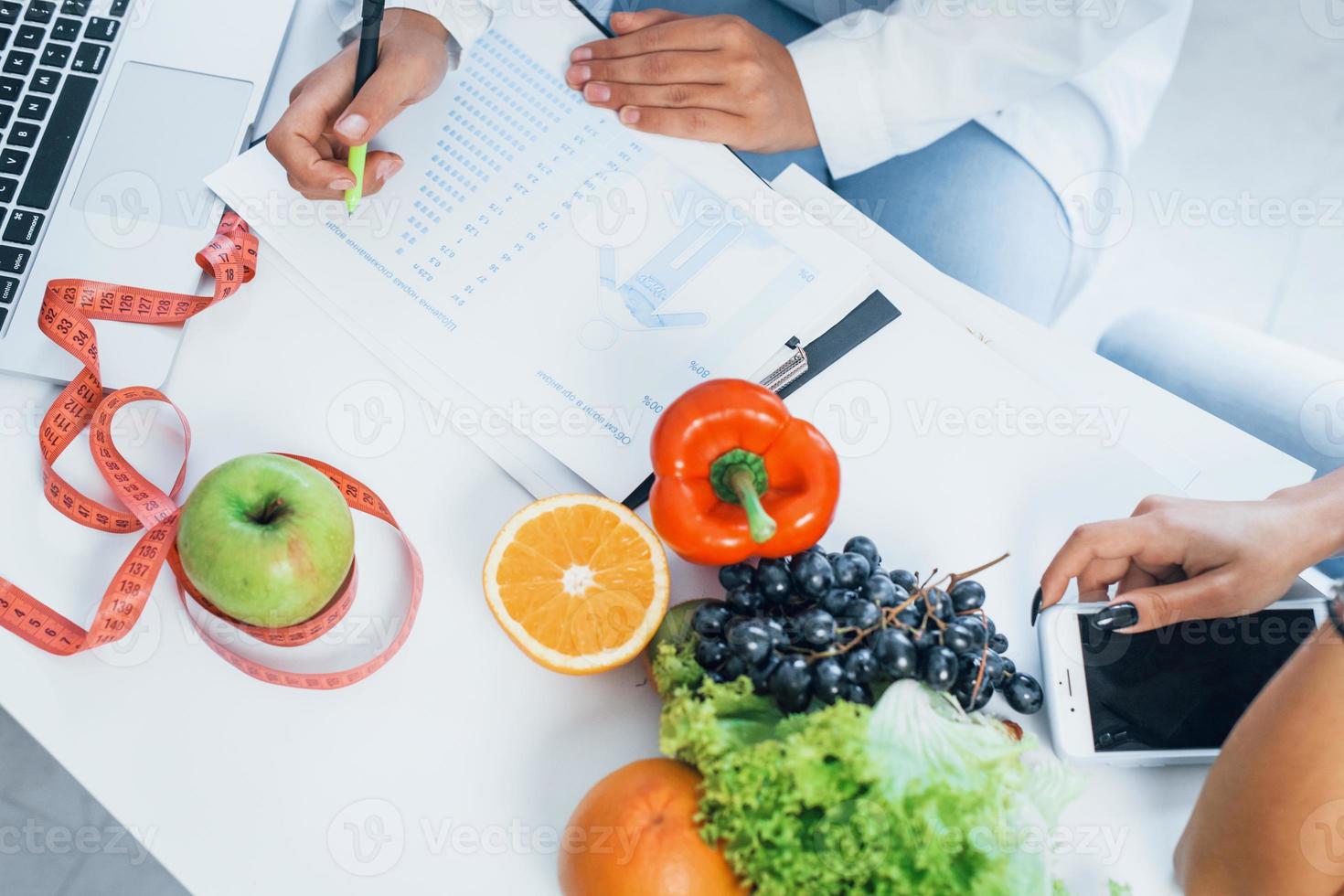 Top view of female nutritionist that gives consultation to patient indoors in the office photo