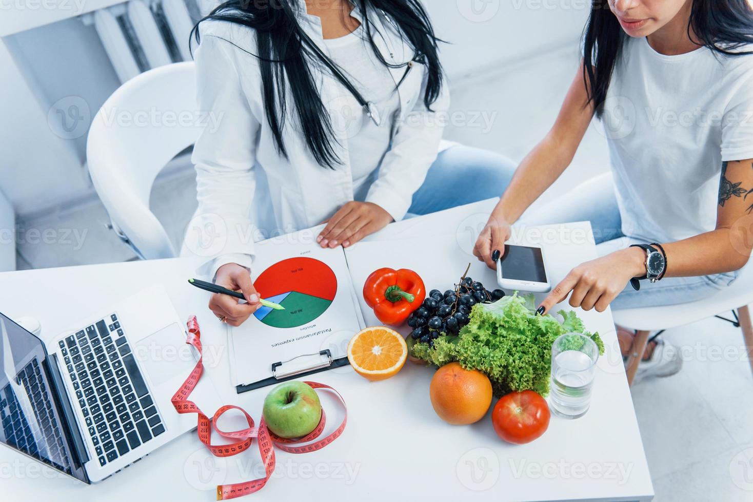 Top view of female nutritionist that gives consultation to patient indoors in the office photo