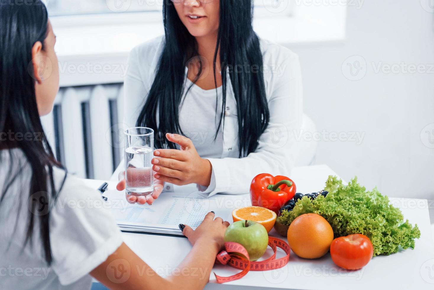 Female nutritionist gives consultation to patient indoors in the office photo