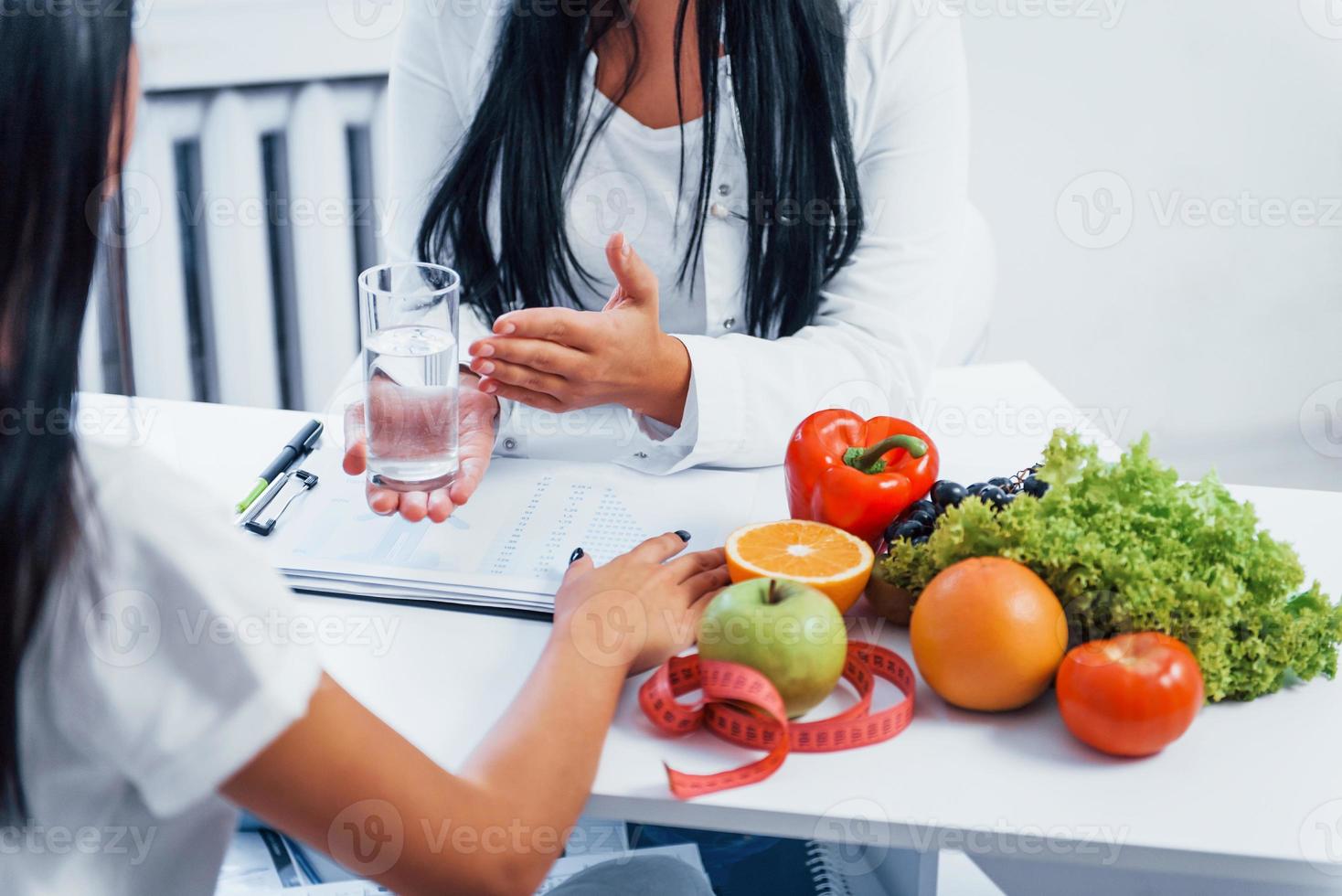 Female nutritionist gives consultation to patient indoors in the office photo