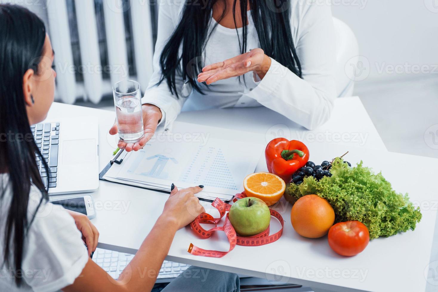 Female nutritionist gives consultation to patient indoors in the office photo