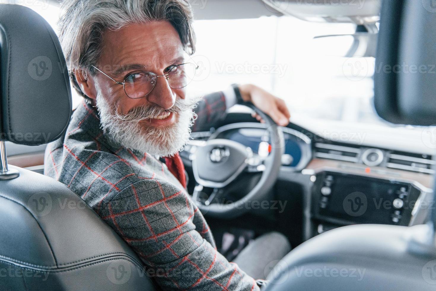 Positive stylish senior man with grey hair and mustache looks back in