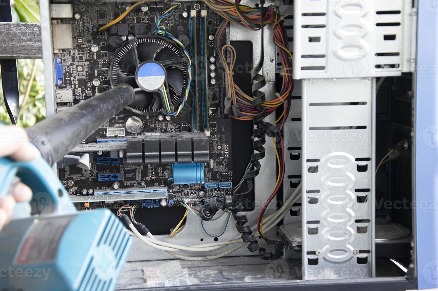 Photograph of a technician blowing dust from a computer photo
