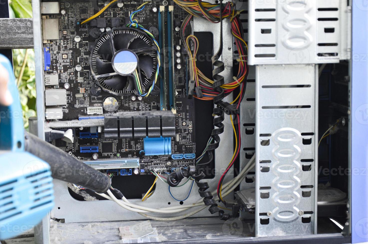 Photograph of a technician blowing dust from a computer photo