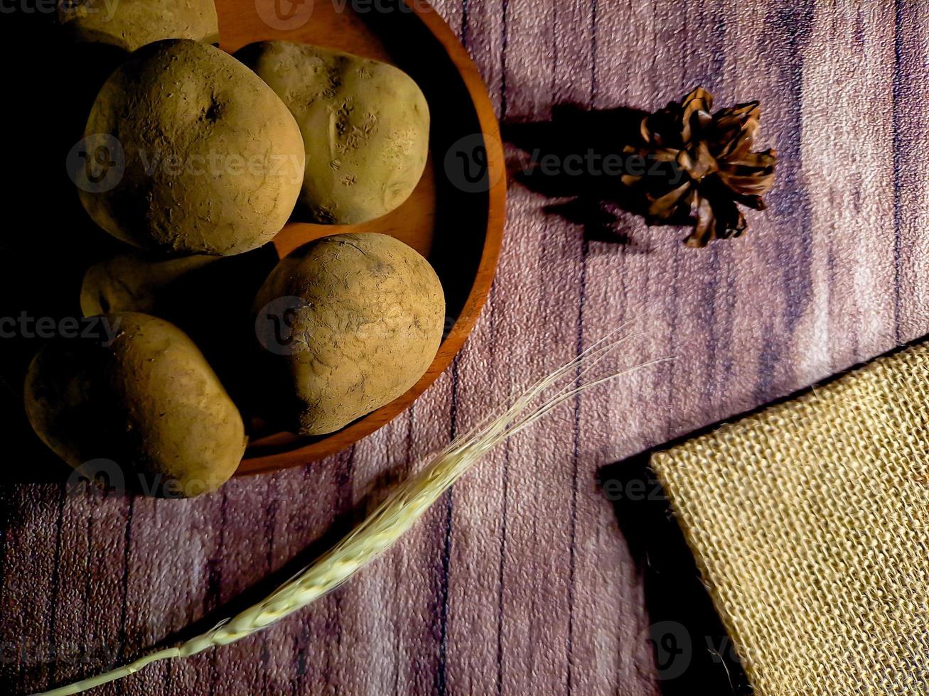 Pile of raw potatoes on dark wooden background. Preparation of potato soup or dish, perfect for advertising brochure background photo
