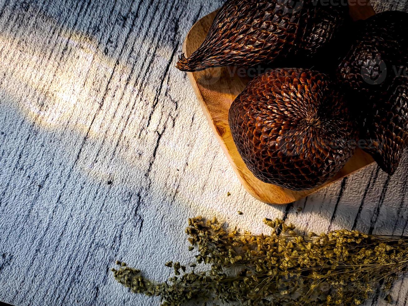 Salak is a type of palm fruit commonly eaten. snake fruit, its scientific name is Salacca zalacca. white wood background. photo