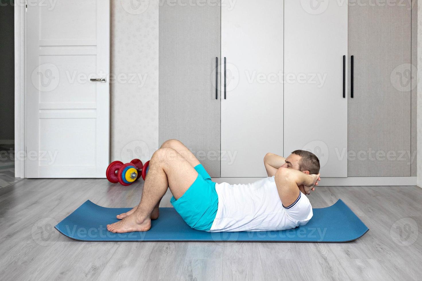 A strong, healthy man with muscles, training at home. Exercises for the muscles of the press photo