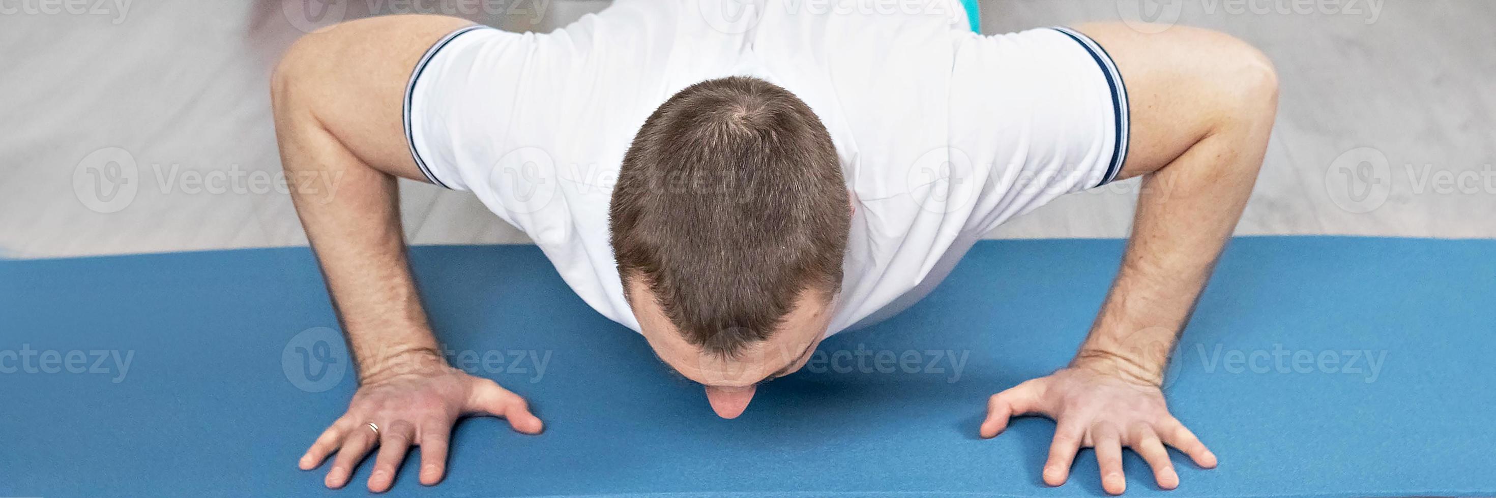 A strong, healthy man with muscles, training at home in the plank position. Fitness at home. Banner photo