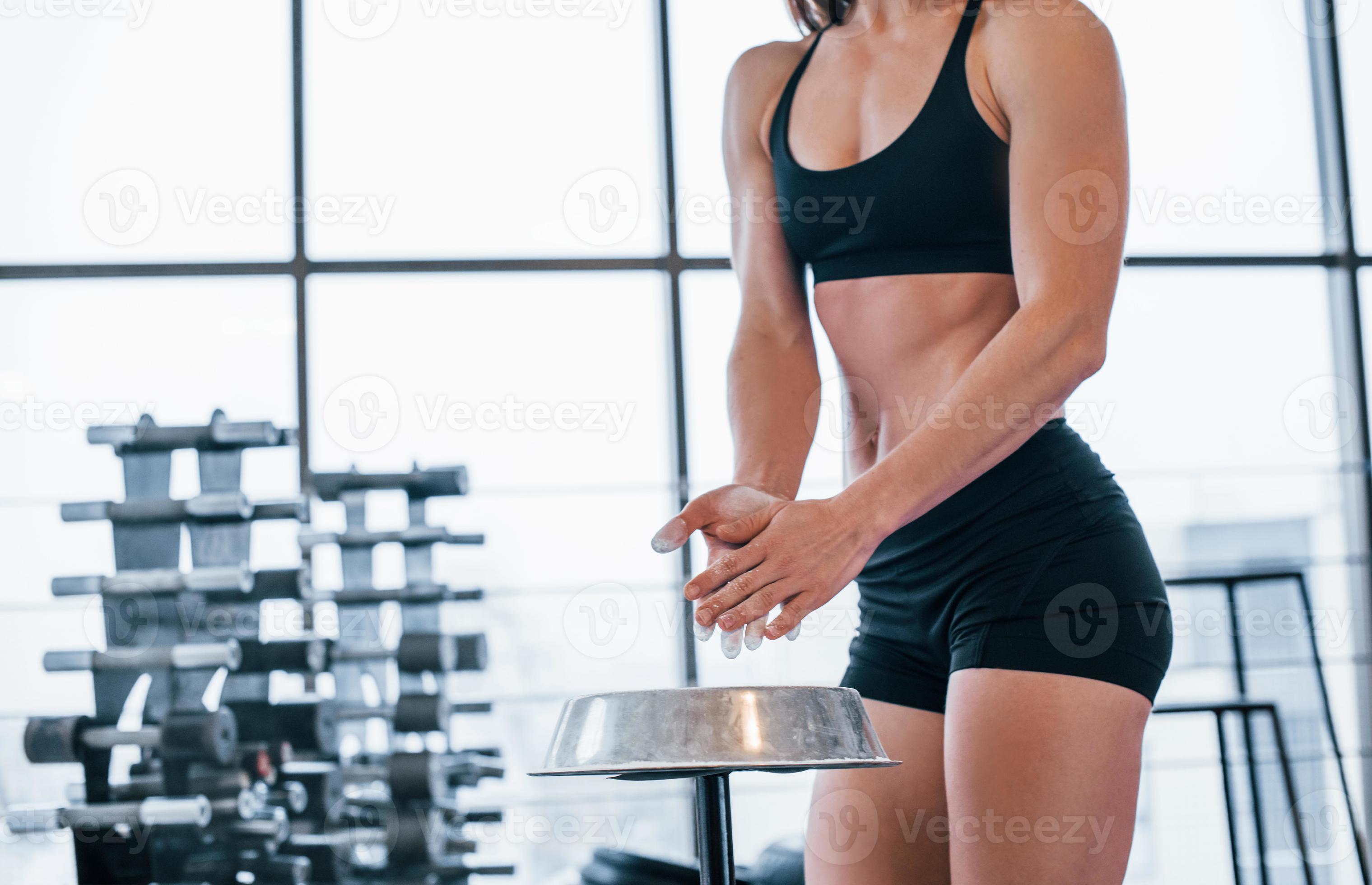 mujer con ropa deportiva negra parada en el gimnasio y