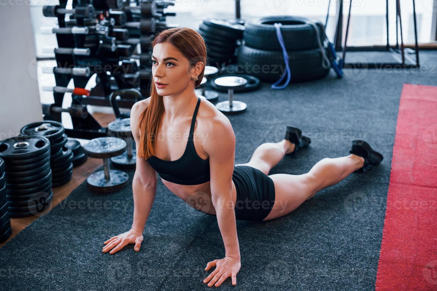 Young sportive woman in black clothes doing stretching exercises in the gym photo