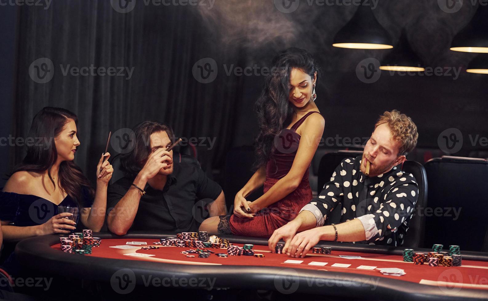 Group of elegant young people that playing poker in casino together photo