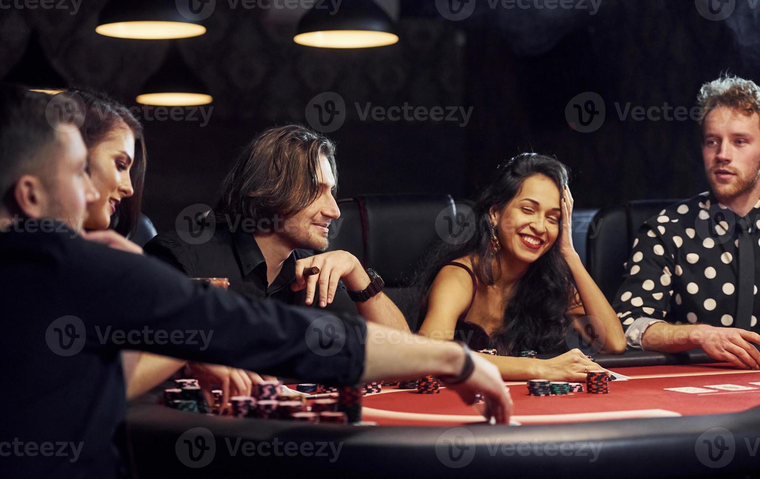 Group of elegant young people that playing poker in casino together photo