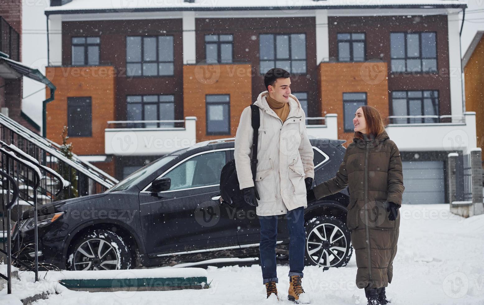 Young couple have a walk together outdoors near car at winter time photo