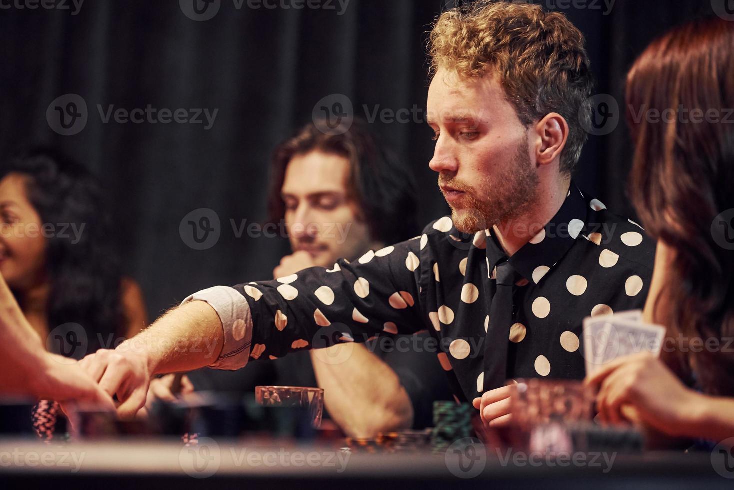 Group of elegant young people that playing poker in casino together photo