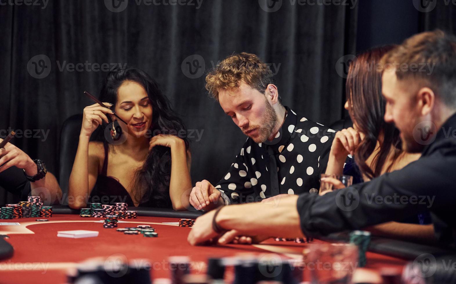 Group of elegant young people that playing poker in casino together photo