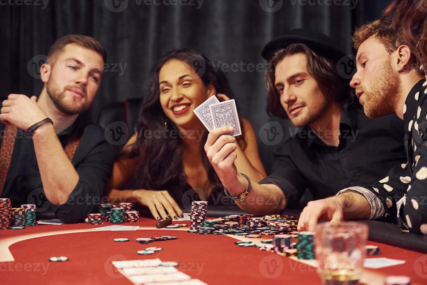 With glasses of drink. Group of elegant young people that playing poker in casino together photo