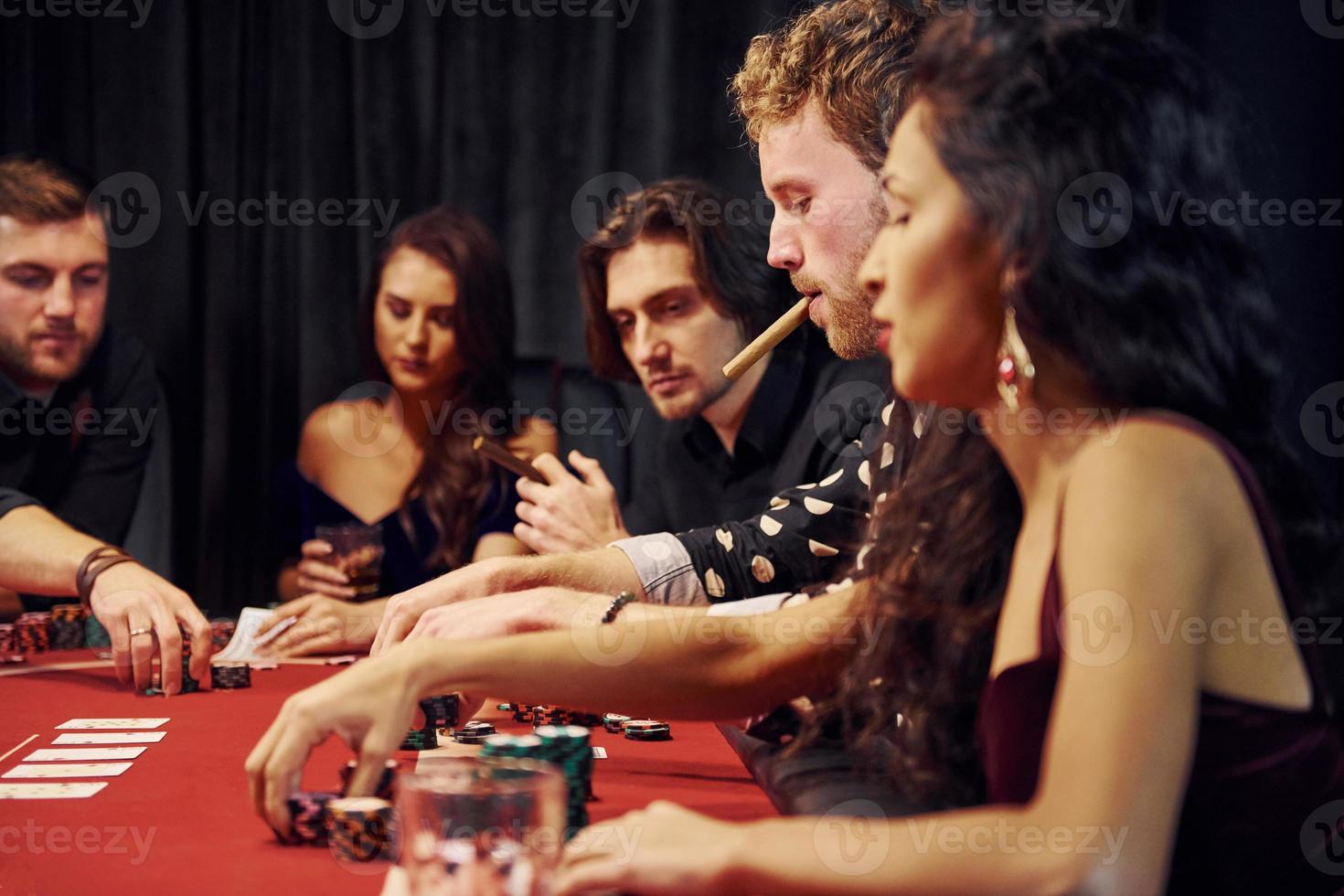 Group of elegant young people that playing poker in casino together photo