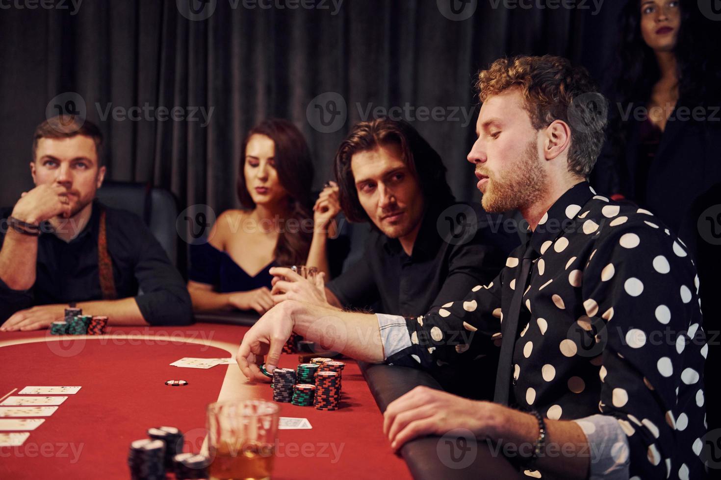 Side view of group of elegant young people that playing poker in casino together photo