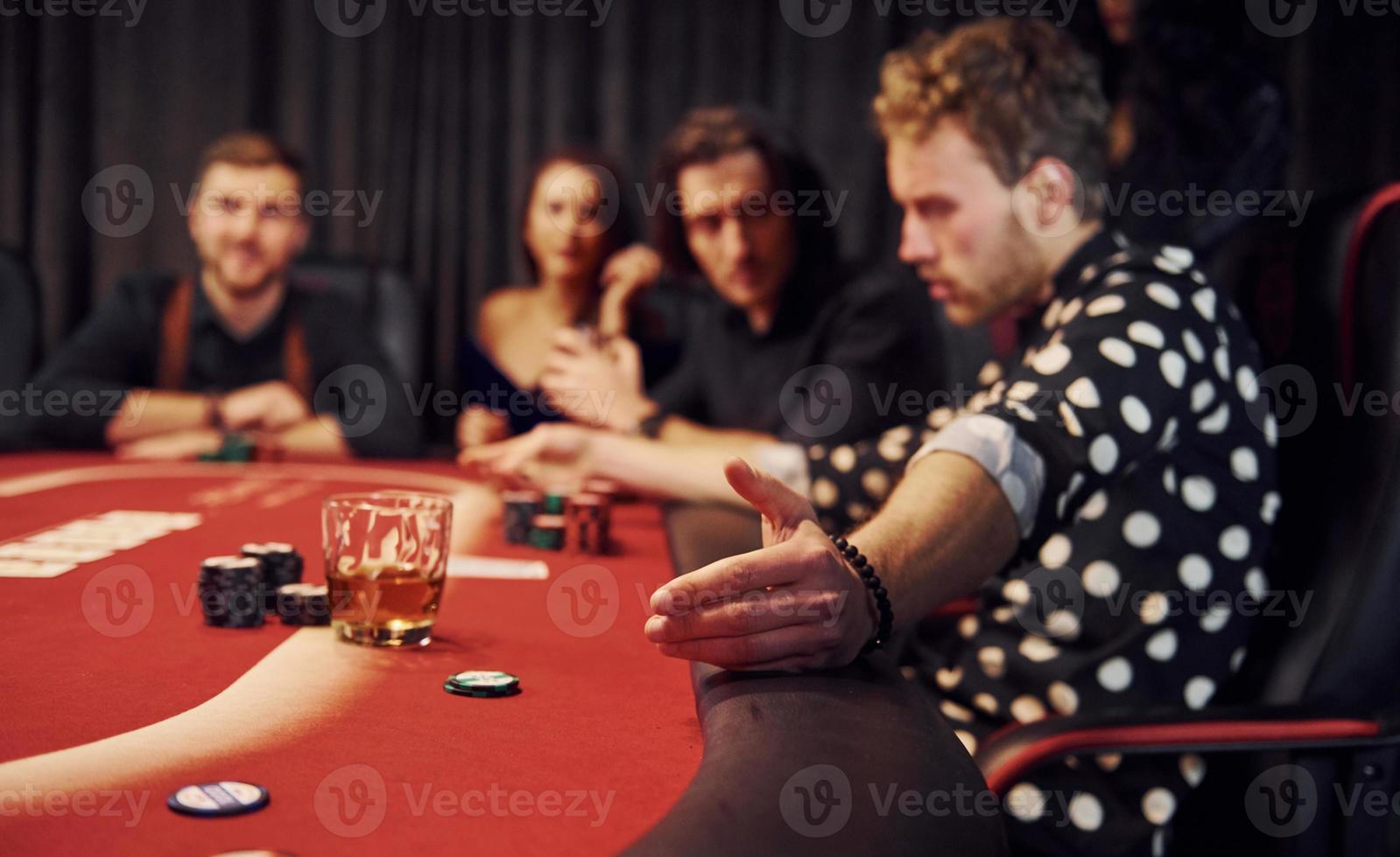 Side view of group of elegant young people that playing poker in casino together photo