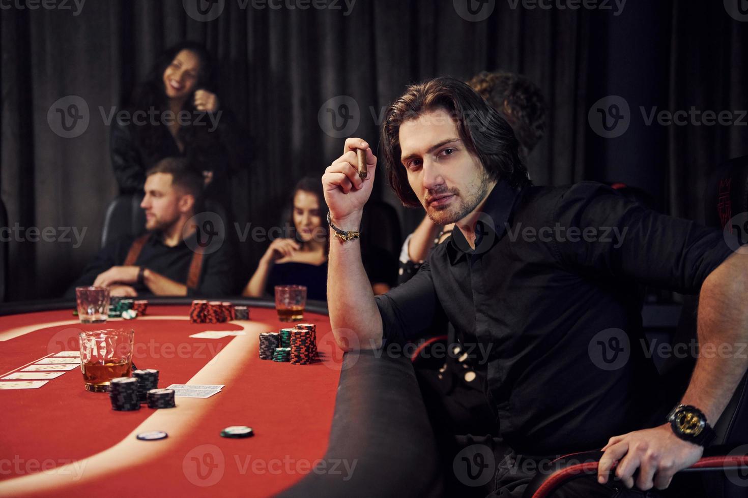 Group of elegant young people that playing poker in casino together photo