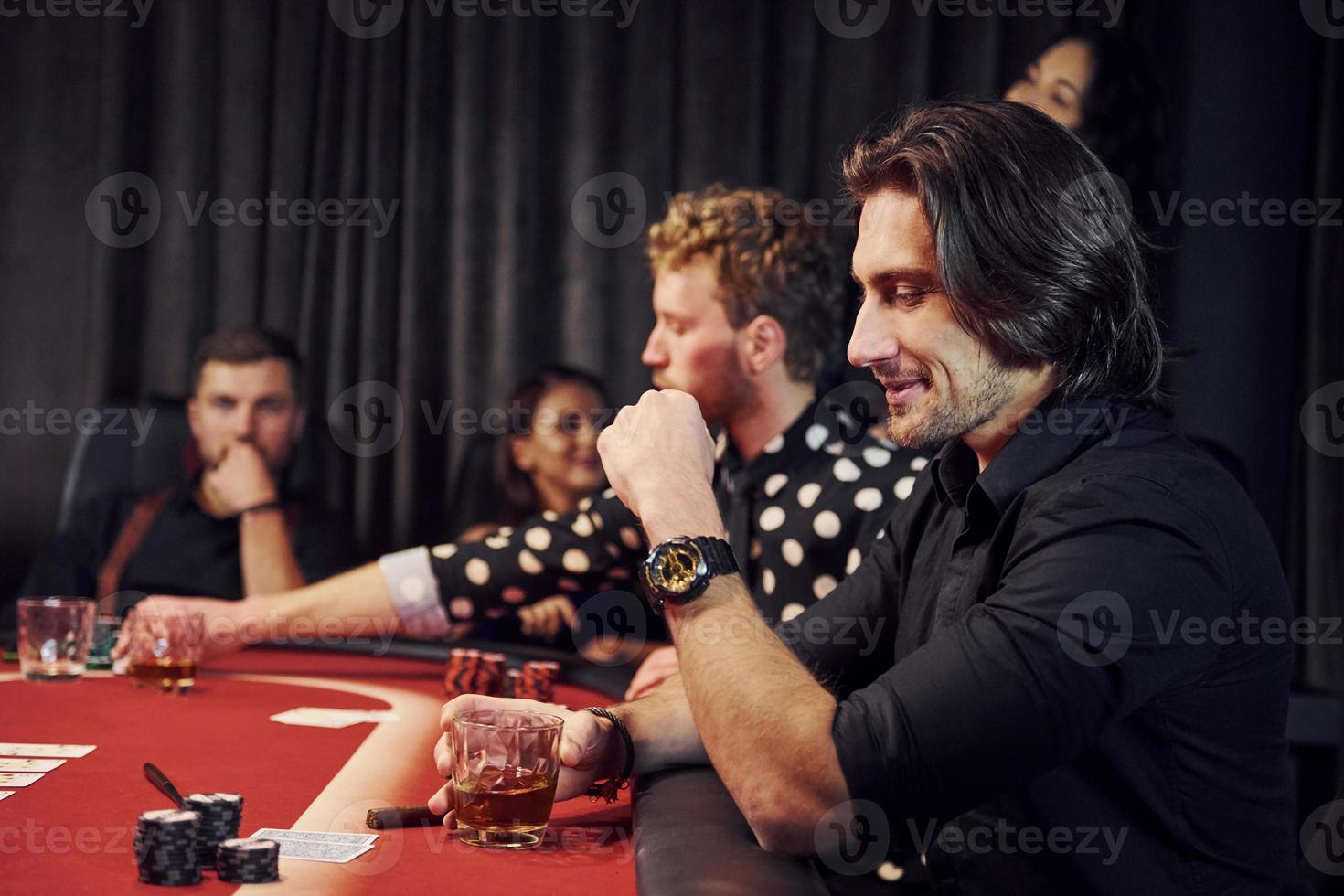 Group of elegant young people that playing poker in casino together photo