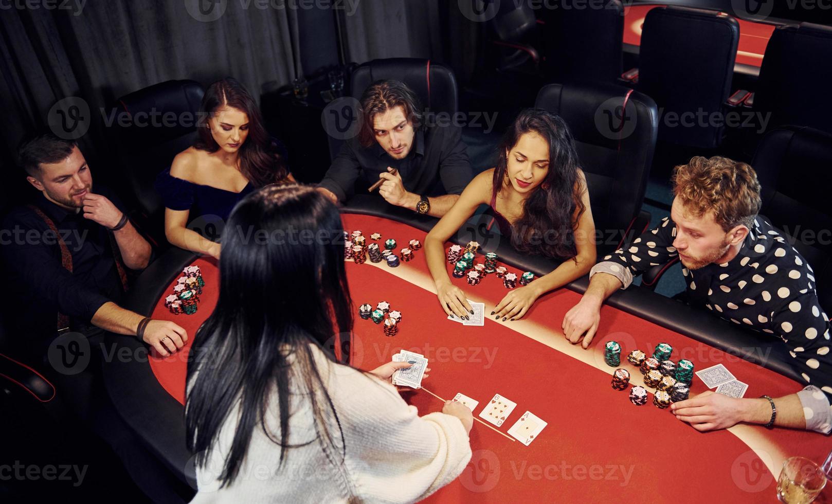 Group of elegant young people that playing poker in casino together photo