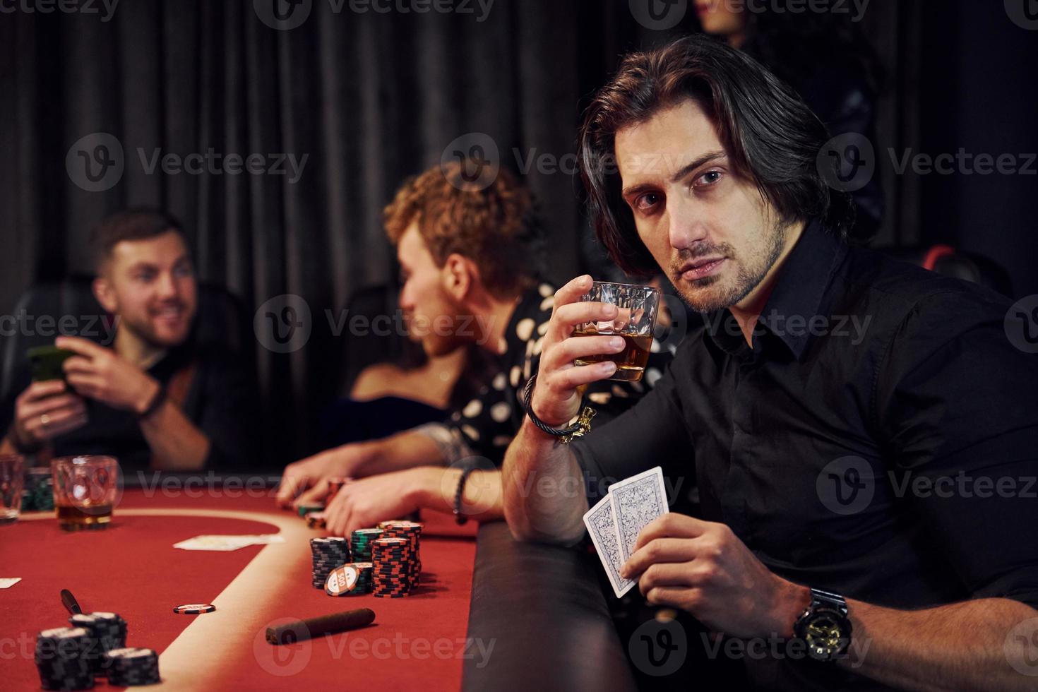 Group of elegant young people that playing poker in casino together photo