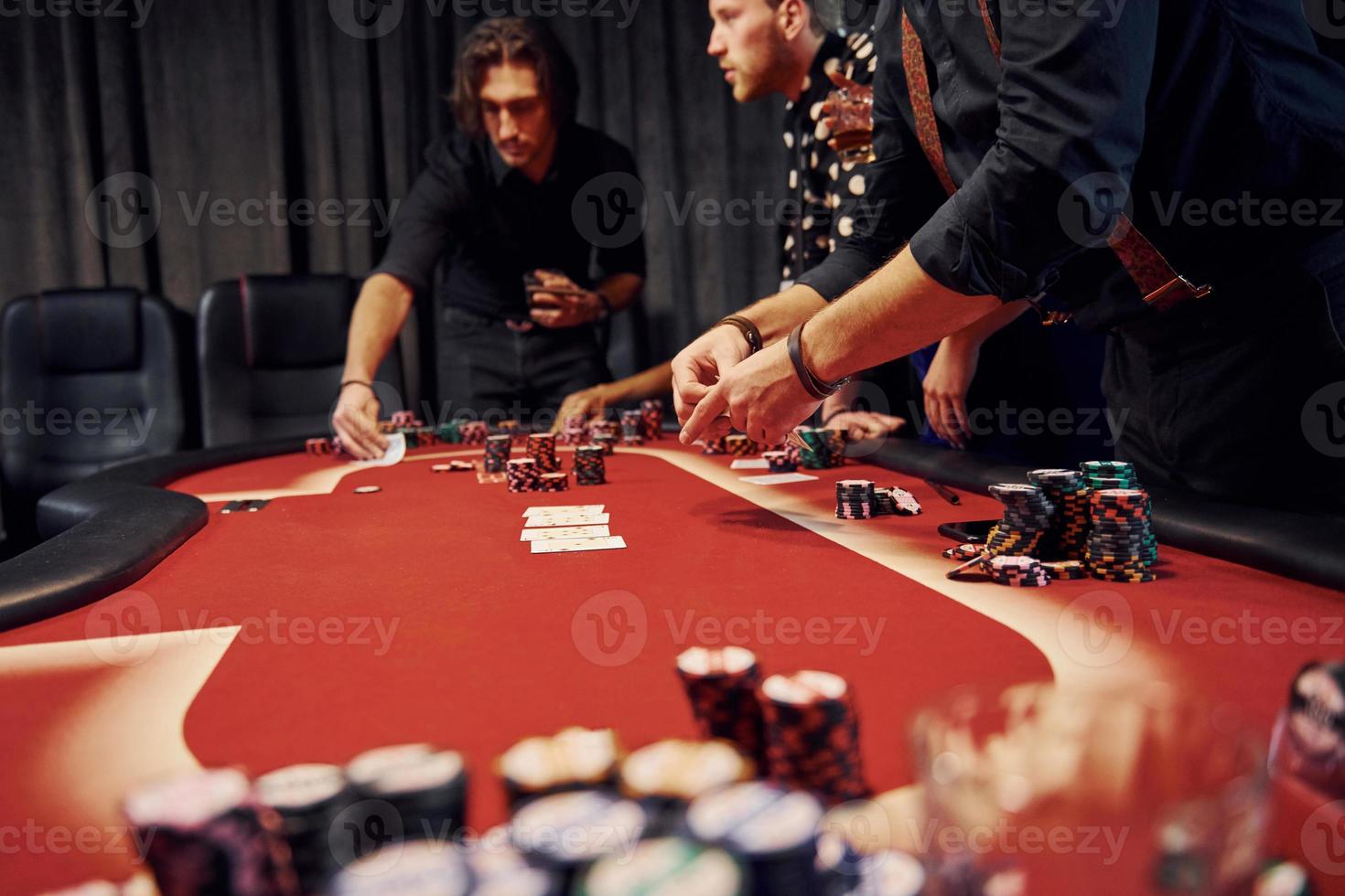 People in elegant clothes standing and playing poker in casino together photo