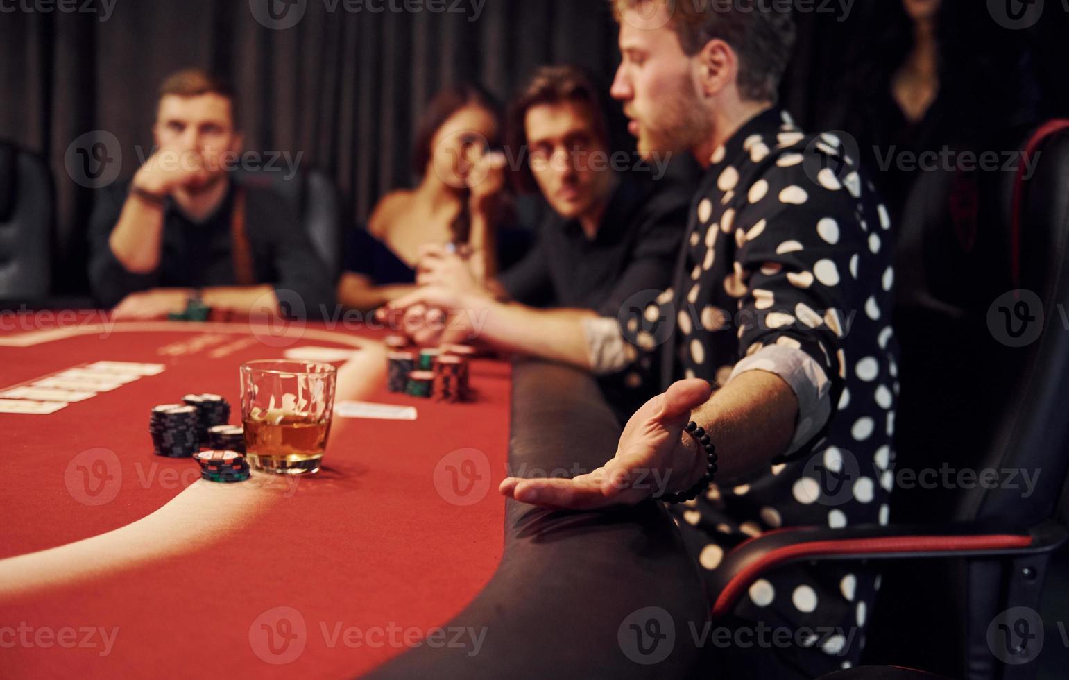 Side view of group of elegant young people that playing poker in casino together photo