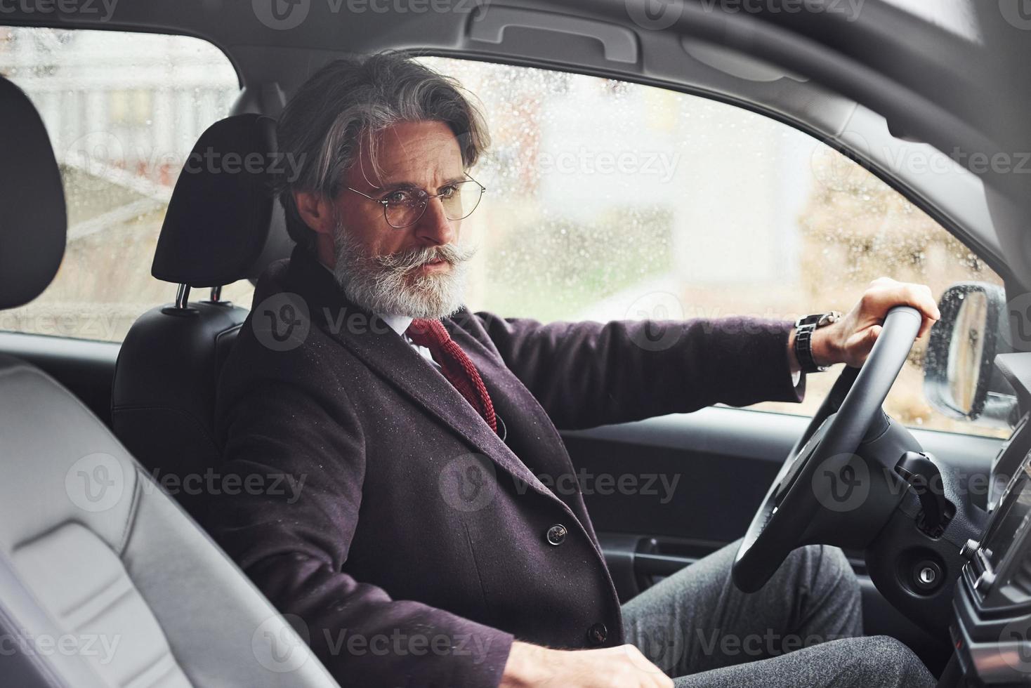 Fashionable senior man in elegant clothes is in the modern car photo