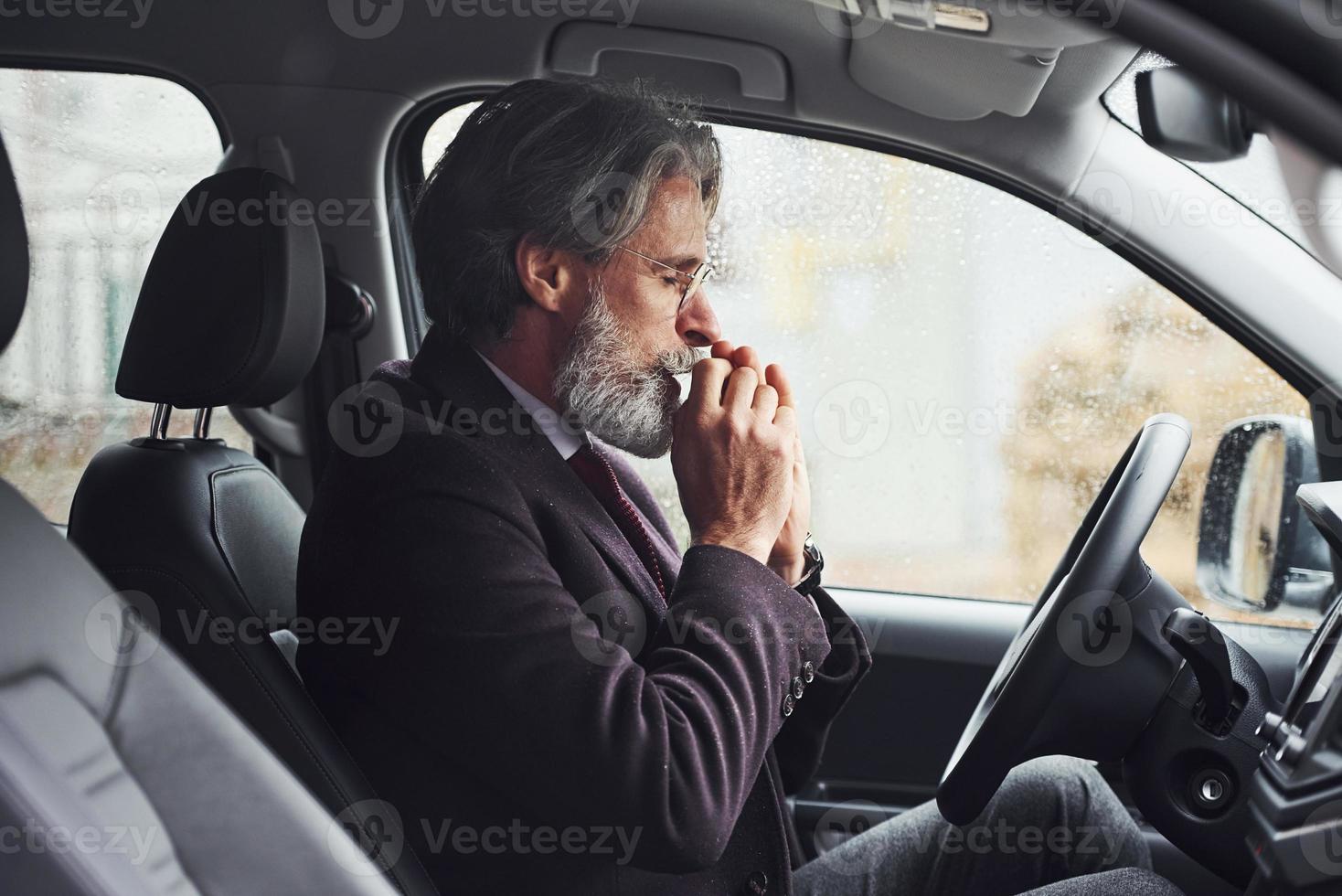 Fashionable senior man in elegant clothes is in the modern car photo