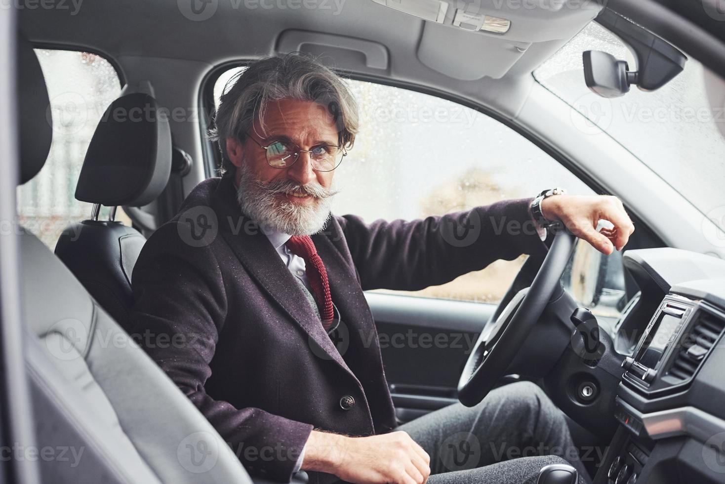 Fashionable senior man in elegant clothes is in the modern car photo